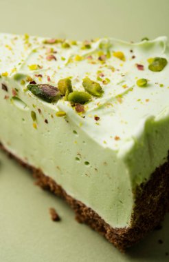 Görme yeşili arka planda bir dilim antep fıstığı cheesecake