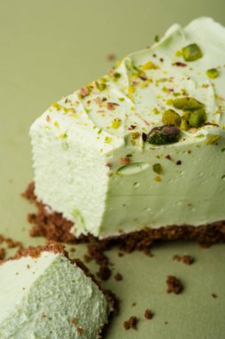 Görme yeşili arka planda bir dilim antep fıstığı cheesecake