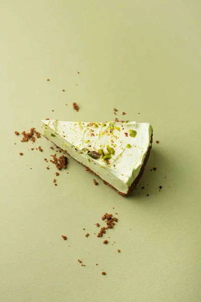 One slice of pistachio cheesecake on sight green background — Stock Photo, Image