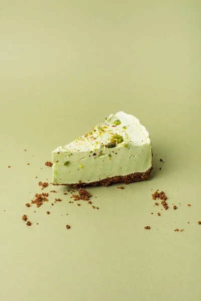 One slice of pistachio cheesecake on sight green background — Stock Photo, Image