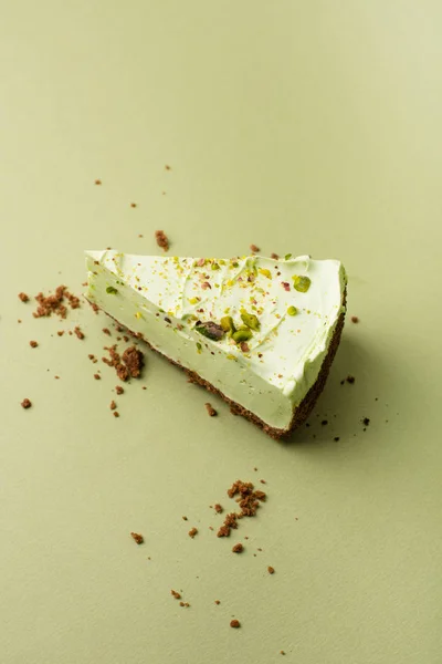 One slice of pistachio cheesecake on sight green background — Stock Photo, Image