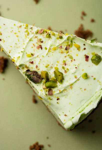 One slice of pistachio cheesecake on sight green background — Stock Photo, Image