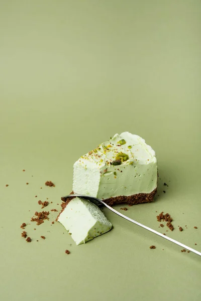 One slice of pistachio cheesecake on sight green background — Stock Photo, Image