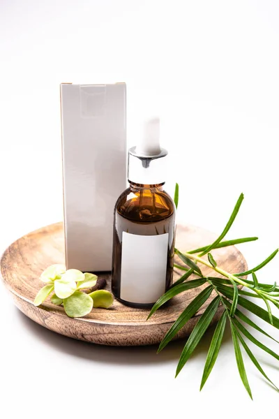 Kahverengi cam kozmetik şişe mock-up boş beyaz etiket ve yeşil yaprakları, serum ambalaj ile — Stok fotoğraf