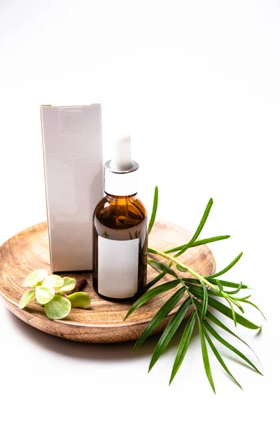Kahverengi cam kozmetik şişe mock-up boş beyaz etiket ve yeşil yaprakları, serum ambalaj ile — Stok fotoğraf