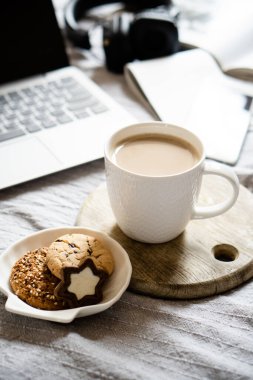 Gerçek ev işyeri, bir fincan kahveli dizüstü bilgisayar, sıcak battaniyeli kurabiye.