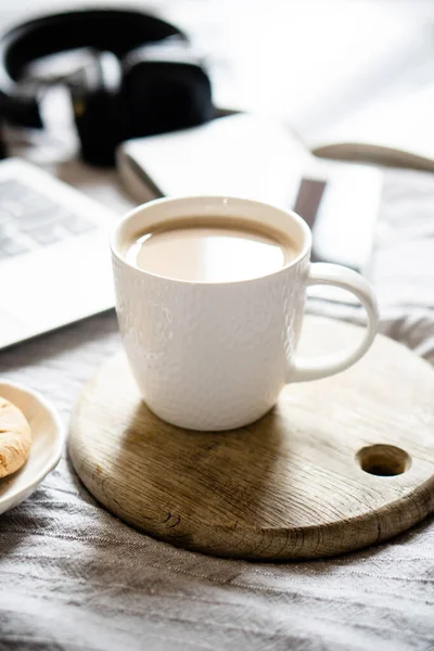 Real home workplace, laptop with cup of coffee with cookies on bed with cozy blanket — Stock Photo, Image