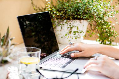 Kadın elleri dizüstü bilgisayarda, rahat iş yerinde.