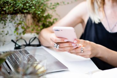 Kadınların el ele tutuştuğu akıllı telefon rahat yaz ofisinde dizüstü bilgisayar ve yeşil bitkilerle