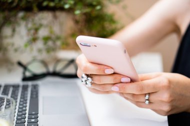 Kadınların el ele tutuştuğu akıllı telefon rahat yaz ofisinde dizüstü bilgisayar ve yeşil bitkilerle