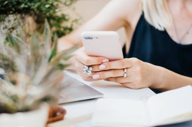 Kadınların el ele tutuştuğu akıllı telefon rahat yaz ofisinde dizüstü bilgisayar ve yeşil bitkilerle
