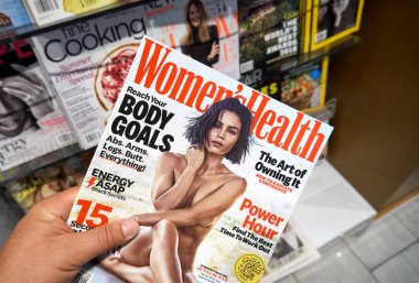 Miami, Amerika Birleşik Devletleri - 22 Ağustos 2018: Kadın Sağlığı Dergisi Dergi yığınının üzerinde bir el. Bir popüler dergisi odaklanarak sağlık, beslenme, fitness, seks kadın sağlığı olduğunu