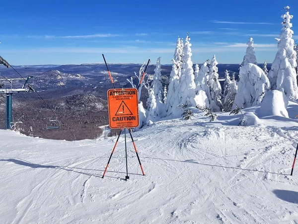 Caution sign and warning on a ski resort about unmarked rocks and obstacles in the beginning of a trail.