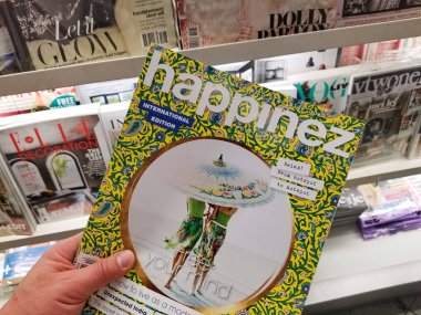 Amsterdam, Hollanda: - 8 Ekim 2018: Happinez Dergisi Dergi yığınının üzerinde bir elinde. Happinez bilge, olumlu ve sevgi dolu bir hayat hakkında bir Hollandalı popüler dergi olduğunu.