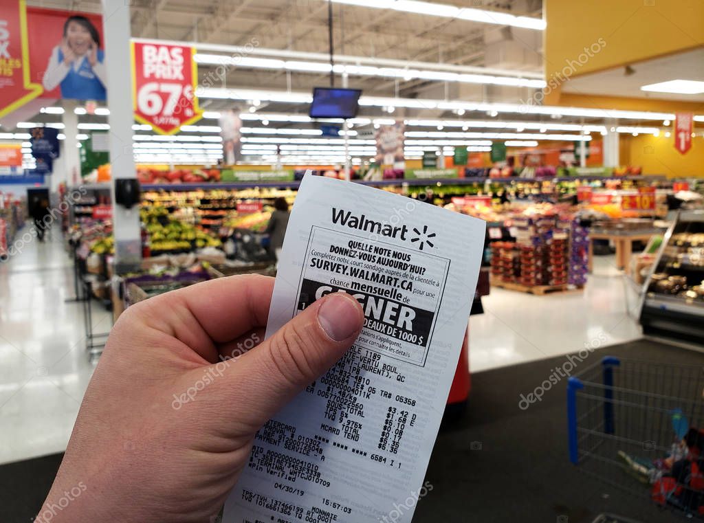 MONTREAL, CANADA - APRIL 30, 2019: A hand holding a Walmart receipt in Walmart store. Walmart is an American retail corporation that operates a chain of hypermarkets and discount department store