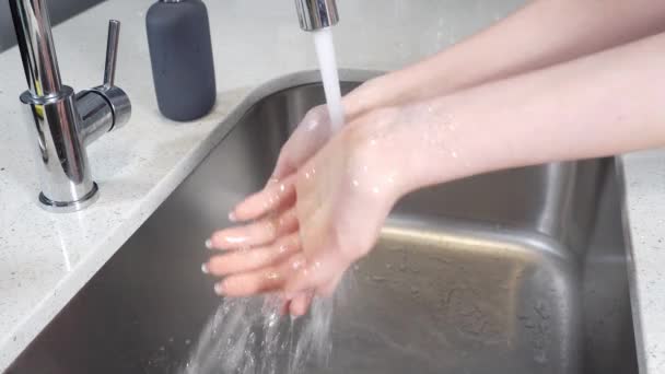 A girl rinses her hands under the faucet in the kitchen. — Stock Video