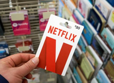 Montreal, Canada - May 03, 2020: Netflix gift card in a hand over a stand with gift cards. Netflix is a streaming service that allows to watch TV shows, movies and documentaries