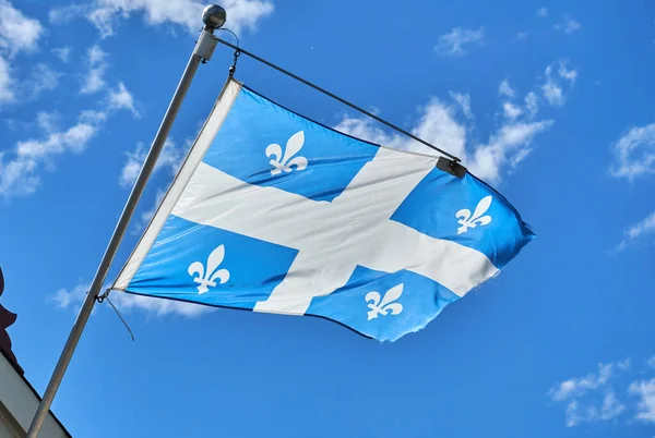 The waving flag of Quebec over a blue sky background. The flag of Quebec, called the Fleurdelise represents the Canadian province of Quebec, the flag consists of a white cross on a blue background