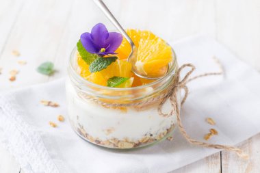 Yoğurt, granola ve portakal cam kavanozda.
