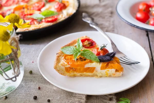 ショートクラストペストリー 赤と黄色のトマト チーズ クリームで作られたトマトタルト 素朴な木製の背景に健康的な食べ物やベジタリアン食品の概念 — ストック写真