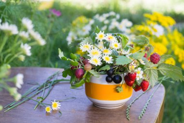 Çiçek buketi ve fincanda böğürtlen