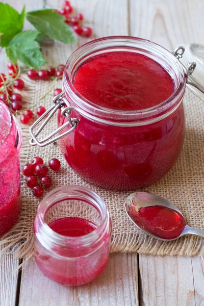 Red currant jam in glass jar on wooden table