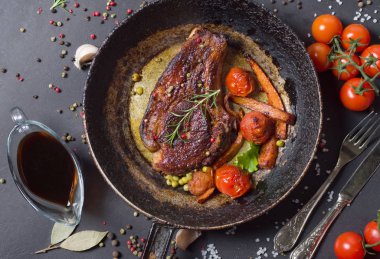 bir tava üzerinde sebzeli ızgara biftek