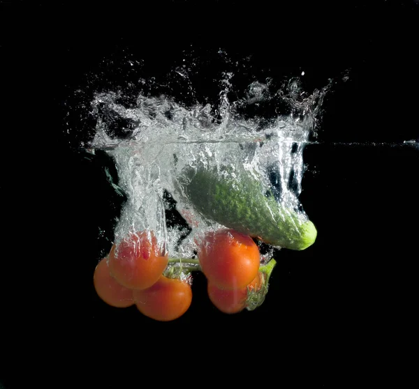在黑色背景下气泡的水中的西红柿和黄瓜 — 图库照片
