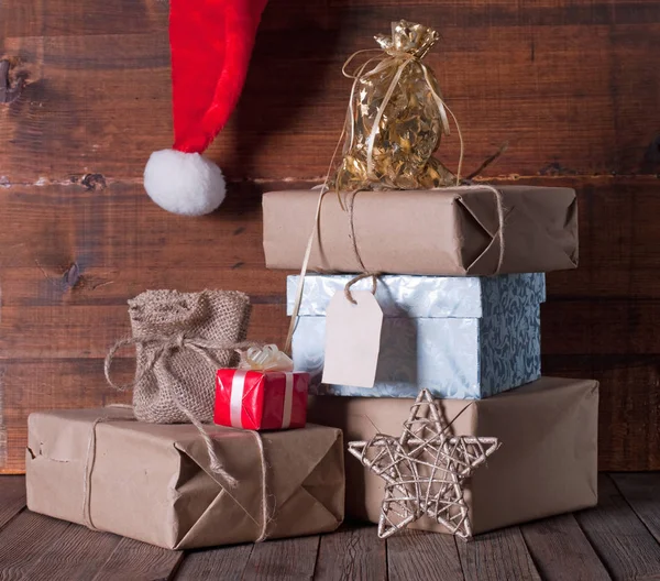 Schachteln Mit Weihnachtsgeschenken Und Weihnachtsmütze Auf Holzgrund — Stockfoto