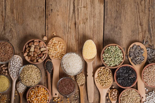 Cereal grains , seeds, beans on wooden background.