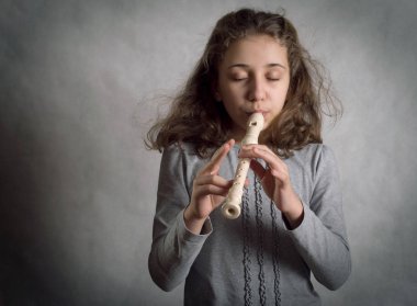 Kız flüt gri bir arka plan üzerinde oynama