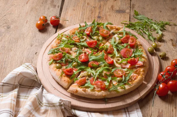 Roka ve domates pizza ahşap tahta üzerinde dilimlenmiş