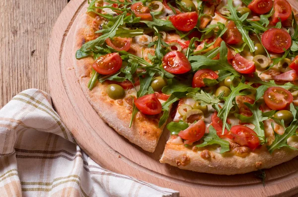 Roka ve domates pizza ahşap tahta üzerinde dilimlenmiş