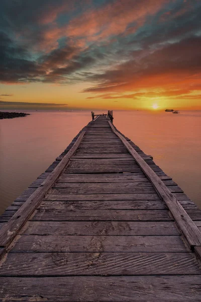 劇的な夕日と海に伸びる古い木製の桟橋 — ストック写真