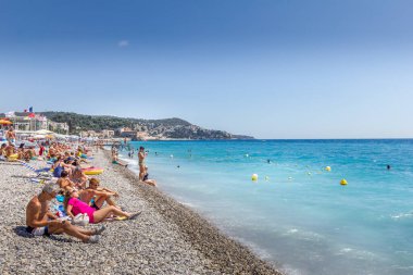 Güzel, Fransa - 23 Ağustos 2015: Turistler sahilde güzel havanın tadını çıkarıyorlar. Sahil ve liman bulvarı, Promenade des Anglais, neredeyse tüm yıl dolu..