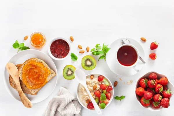 オートミールのポリッジ ストロベリー ナッツ トースト ジャム 紅茶と健康的な朝食 トップ ビュー — ストック写真