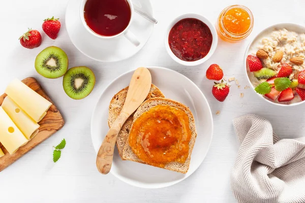 オートミールのポリッジ ストロベリー ナッツ トースト ジャム 紅茶と健康的な朝食 トップ ビュー — ストック写真