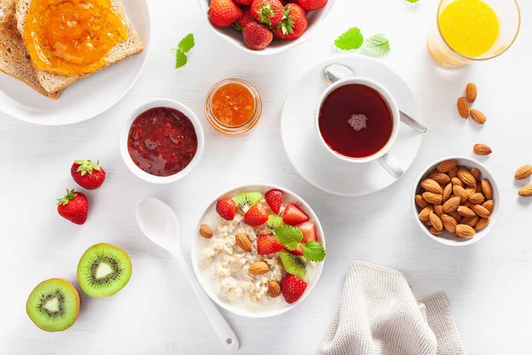 Gezond Ontbijt Met Havermoutpap Aardbeien Noten Toast Jam Thee Bovenaanzicht — Stockfoto