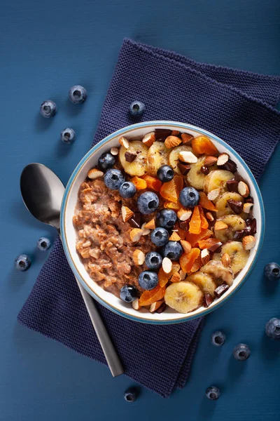 chocolate oatmeal porridge with blueberry, nuts, banana, dried apricot for healthy breakfast. Top view