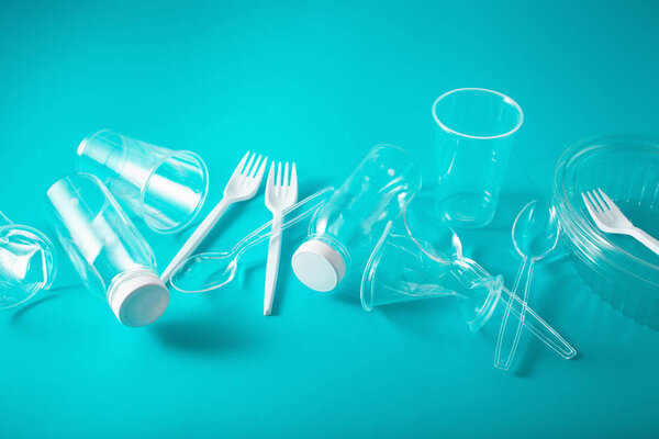 single use plastic bottles, cups, forks, spoons. concept of recy