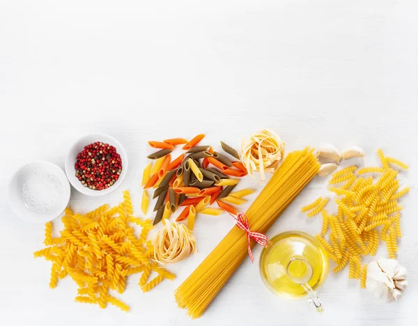 Assorted raw pasta flat lay on white. spaghetti fusilli penne ta — Stock Photo, Image