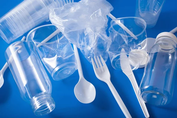 single use plastic bottles, cups, forks, spoons. concept of recy