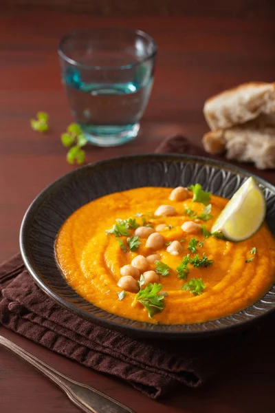 Sopa de garbanzos de zanahoria cremosa sobre fondo rústico oscuro — Foto de Stock