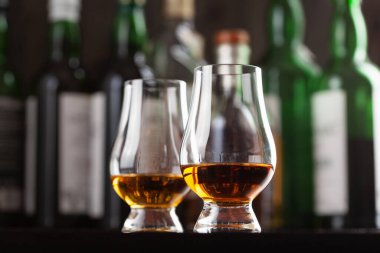 Şişeler ve bir bardak viski. Kahverengi arka planda brendi.