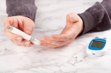 Erkek elleri kan şekeri ve keton seviyelerini glikoz ölçmek için parmak üstüne mızrak kullanır. İlaç diyabeti keto diyet sağlık hizmetleri evde