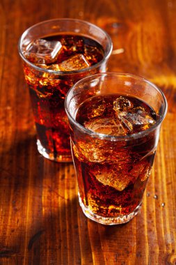 Bir bardak soğuk kola, ahşap zemin üzerinde buz.