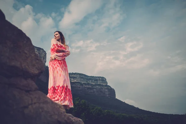 Jonge en mooie vrouw in rode jurk op zoek op bergen. Spanje, Sant Roma de Sau. — Stockfoto