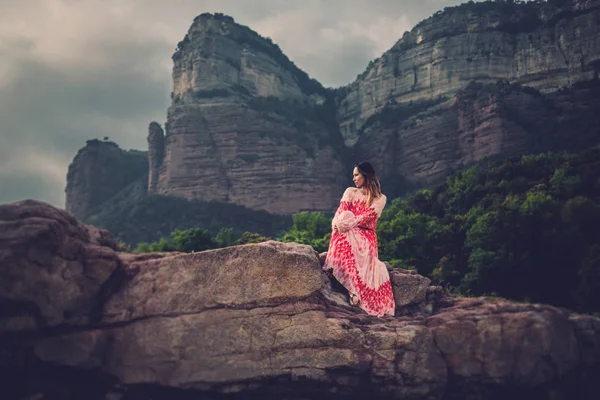 Young beautiful woman in red dress looking on mountains. Spain, Sant Roma de Sau. — Stock Photo, Image