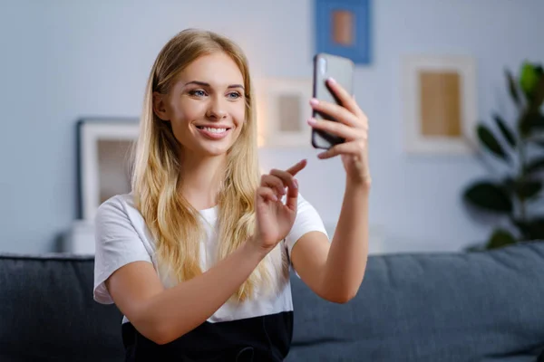 Hermosa mujer usando su teléfono inteligente en la sala de estar — Foto de Stock