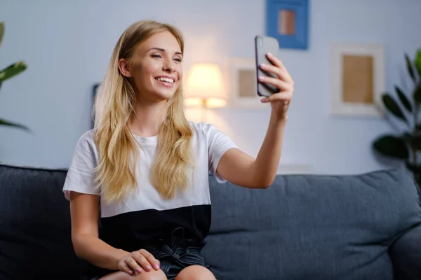 Vacker kvinna med hennes smartphone i vardagsrummet — Stockfoto